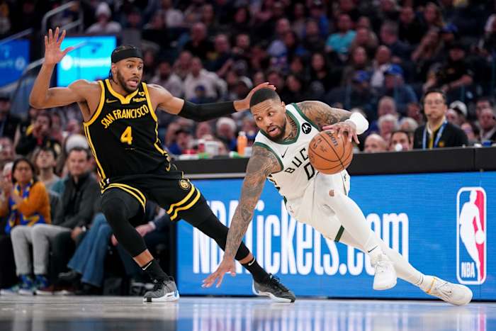 Milwaukee Bucks guard Damian Lillard (0) loses his footing in front of Golden State Warriors guard Moses Moody (4)